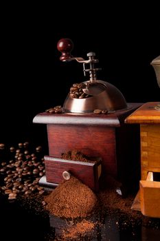 Dark elegant luxurious coffee background. Vintage coffee grinder, ground coffee and coffee beans on black background. Culinary coffee drinking.