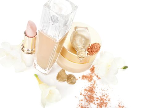 Beige luxurious make up and cosmetic still life. Golden nail polish, beige facial powder and foundation, moisturizer and yellow flowers isolated on white background. 