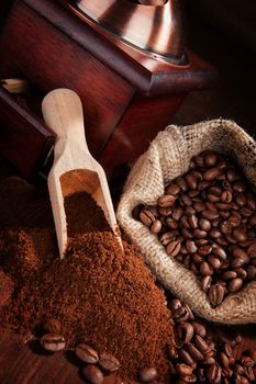 Coffee beans, ground coffee, vintage coffee mill and sack with coffee beans on brown wooden background. Culinary coffee background.