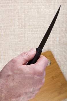 Kitchen knife on a table with a cutting board.