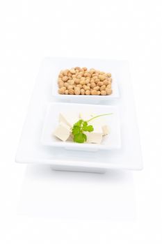 Tofu with green herbs and soybeans in white square bowl isolated on white background. Vegetarian & vegan eating. 