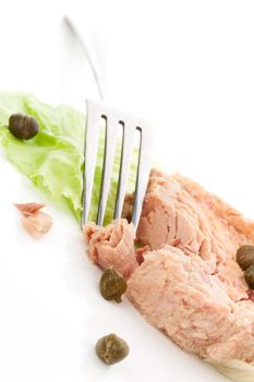 Delicious tuna on lettuce leaf with green capers. Luxurious culinary tuna eating.