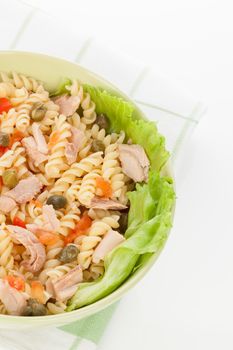 Pasta with capers, tuna and lettuce in green bowl detail. Culinary italian eating.