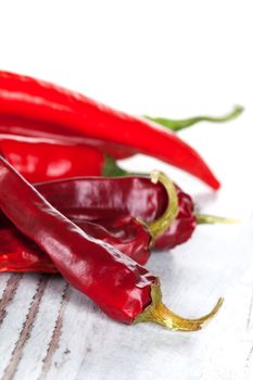 Red hot chili peppers isolated on white wooden textured background. Culinary hot spices. 