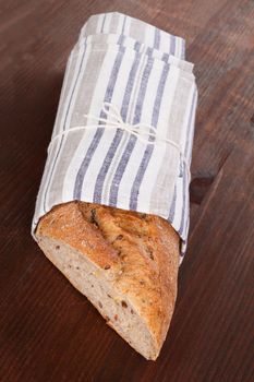 Luxurious dark brown baguette on wooden background, rustic style. Delicious bread eating.