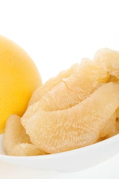 Delicious pomelo still life. Peeled pomelo pieces on plate, whole fruit in background. Healthy summer eating.