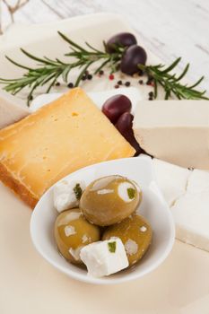 Luxurious olive and cheese background. Green olives and different cheeses, rosemary and peppercorns in bright vintage french country style.