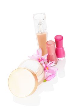 Cosmetics. Cream, nail polish and liquid makeup foundation with pink blossom isolated on white background. Luxurious glamour makeup and cosmetics.
