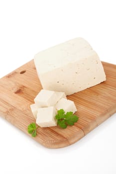 Delicious tofu background. Tofu with fresh parsley on wooden kitchen board isolated on white background. Vegan and vegetarian eating.