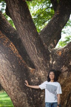 Young woman standing under a large tree. Wearing white shorts.