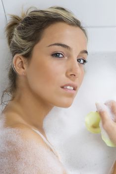nice portrait of a blond girl in bathtub with foam all around in relax
