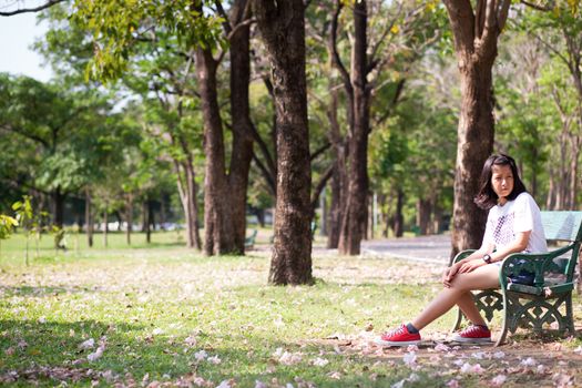 Girl sitting alone on a bench in the park.