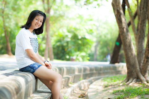 Teenage girl sitting by the road in the park.