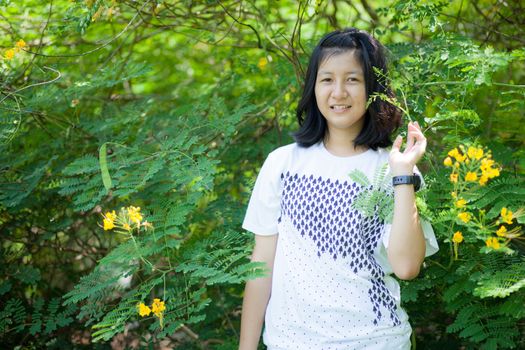 asian girl and yellow flower in park.actie smile and relax.