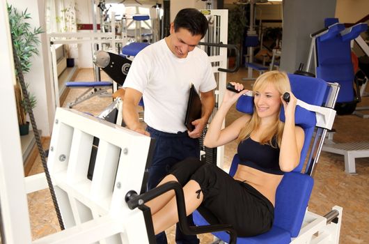 Personal trainer and athletic woman working out in a fitness center