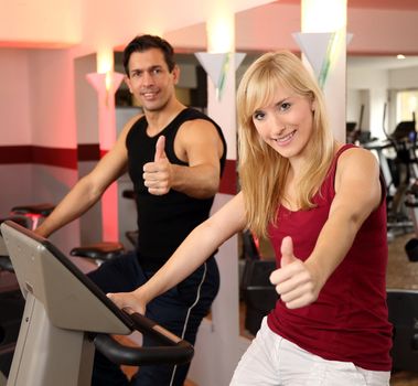 A handsome man and an attractive woman working out on a bicycle in a fitness center