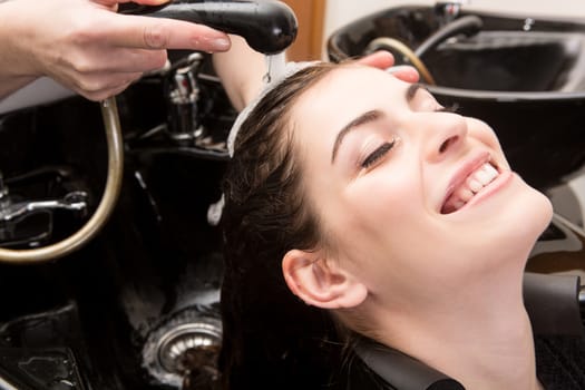 Beautiful woman washing her hair in hairsalon