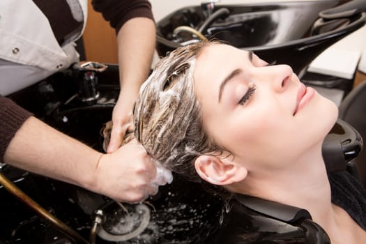 Beautiful woman washing her hair in hairsalon