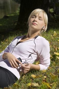 cute blond girl enjoying the sun and listening music with mp3