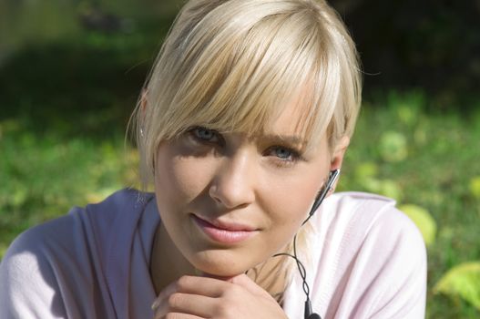 nice portrait of young blond girl with mp3 during a sunny day in the park