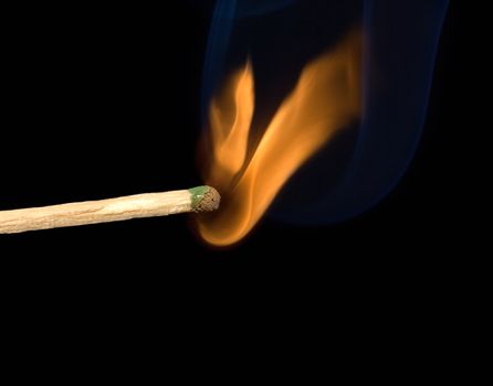 Lighted match and blue smoke on a black background.