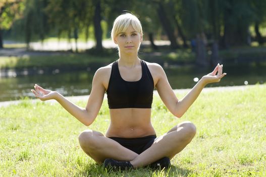 cute blond girl making yoga outdoor in a sunny and warm day