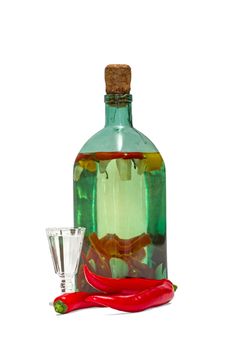 Alcoholate of pepper and garlic in the old green bottle, a glass and chili pepper isolated on a white background.