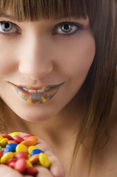 nice portrait of young pretty girl with colored smarties in hand a multi color lips