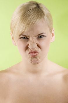 young woman wtih yellow top on green background making funny face