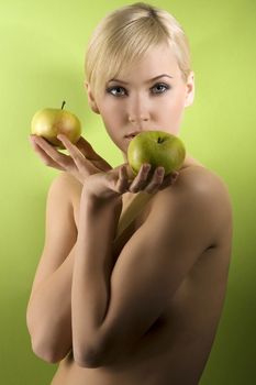 fashion and glamour shot of a nude young woman with apple on green background