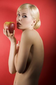 fashion shot of a glamour sensual girl with a red apple and nude body on red colored background