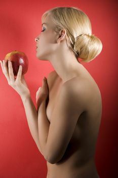 fashion shot of a glamour sensual girl looking a red apple against colored background