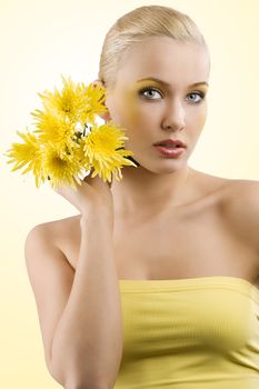 young and beauty blond girl wearing a yellow top keeping yellow flower. wellness concept