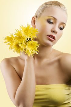 sweet and beauty blond girl wearing a yellow top keeping yellow flower and looking down. wellness concept