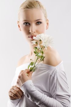beauty portrait of young cute blond girl with white top and some flowers near face