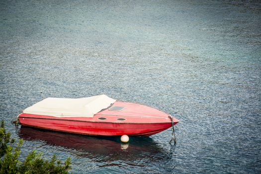Red speed motor boat moored and with white boatcovers on in Mediterraanean water, Mallorca, Balearic islands, Spain.
