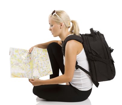 young pretty student girl in vacation sitting down and looking for place on a map