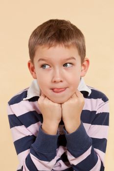 Little caucasian boy sticking out tongue thinking about good food isolated. Culinary gourmet concept.