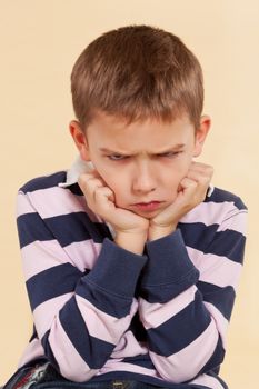 Little angry boy isolated on neutral background. Facial expressions concept.