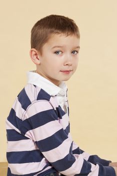 Young cute boy with hollow back sitting and looking into camera isolated. Incorrect posture concept.