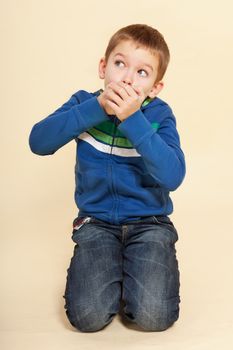 Oh shit, caught. Young boy with hands over his mouth isolated on neutral background. Facial expressions concept. 