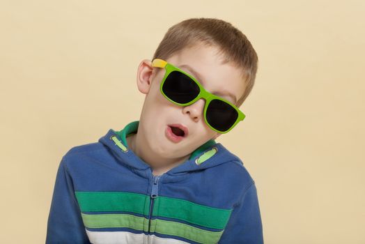 Funky cool young surprised boy with open mouth and yellow and green sunglasses. Youth fashion concept.