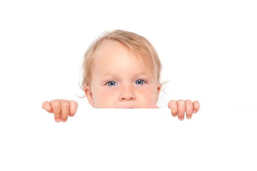 Cute blonde baby girl with big blue eyes looking over white board isolated on white background. Cute curious baby and family concept.