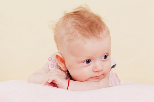 Cute blond newborn baby girl lying on blanket thinking. Beautiful baby concept.