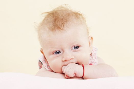 Baby girl lying and looking into the camera and posing. Expressing positivity.