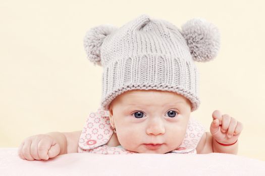 Cute baby girl with grey hat and blue eyes looking into the camera. Newborn baby concept.