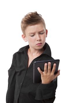 Charming boy in black dress shirt holding tablet, looking at the screen isolated on white background.