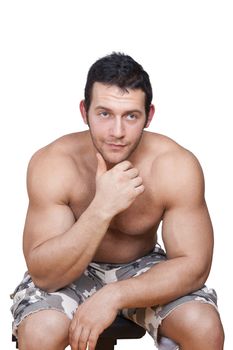 Sexy muscular shirtless athlete sitting, touching chin and looking into camera isolated on white background. Fitness, sport and health background.