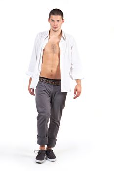 Young male attractive fashion model with white dress shirt and grey pants walking on catwalk isolated on white. Male fashion.
