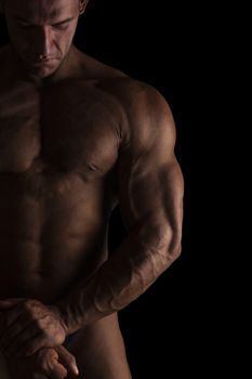 Sexy shirtless bodybuilder isolated on black background. Extreme strenght, muscles and fitness.